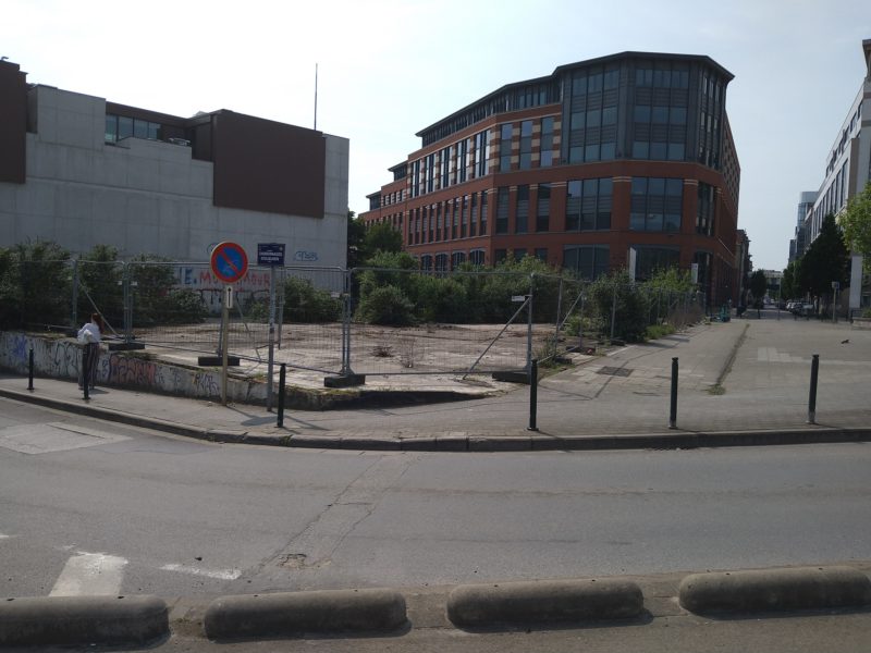 This corner space appears to serve no purpose in the modern city, is currently fenced off, and the overgrown vegetation suggests no imminent reconversion is planned. This space could be reconverted to green space in an area with a large proportion of impermeable surfaces.